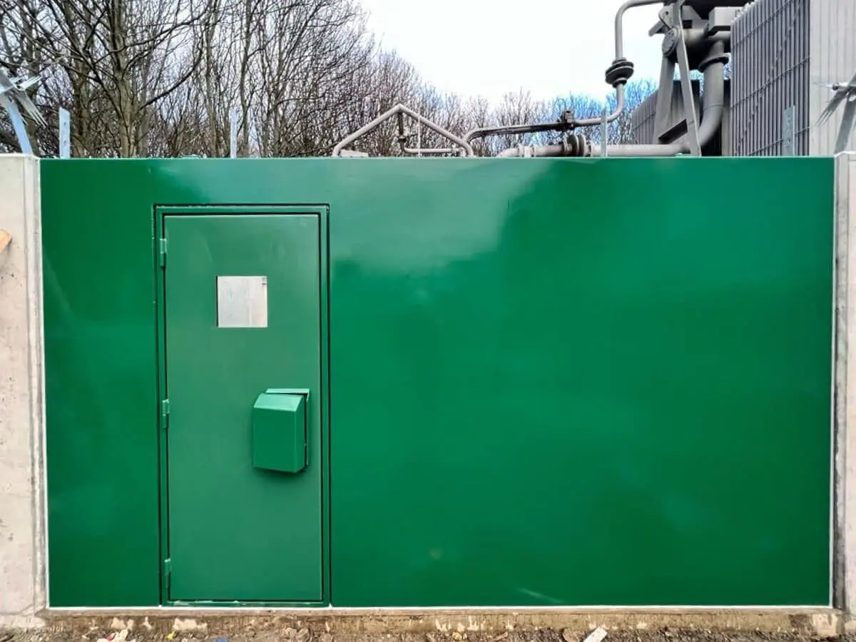 Green flood wall panel with integral access door and letterbox in a substation bund