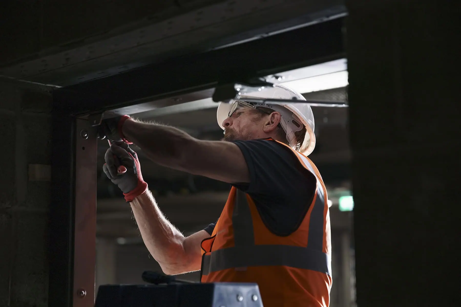 Engineer in hard hat and hi-vis fitting hardware to the frame of a flood door