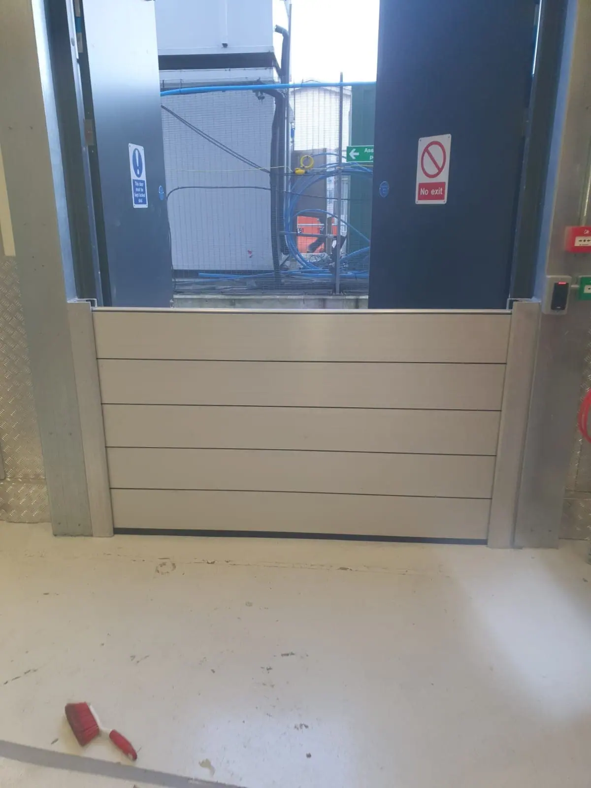 Low aluminium flood barrier panels fitted inside a doorway on an industrial floor