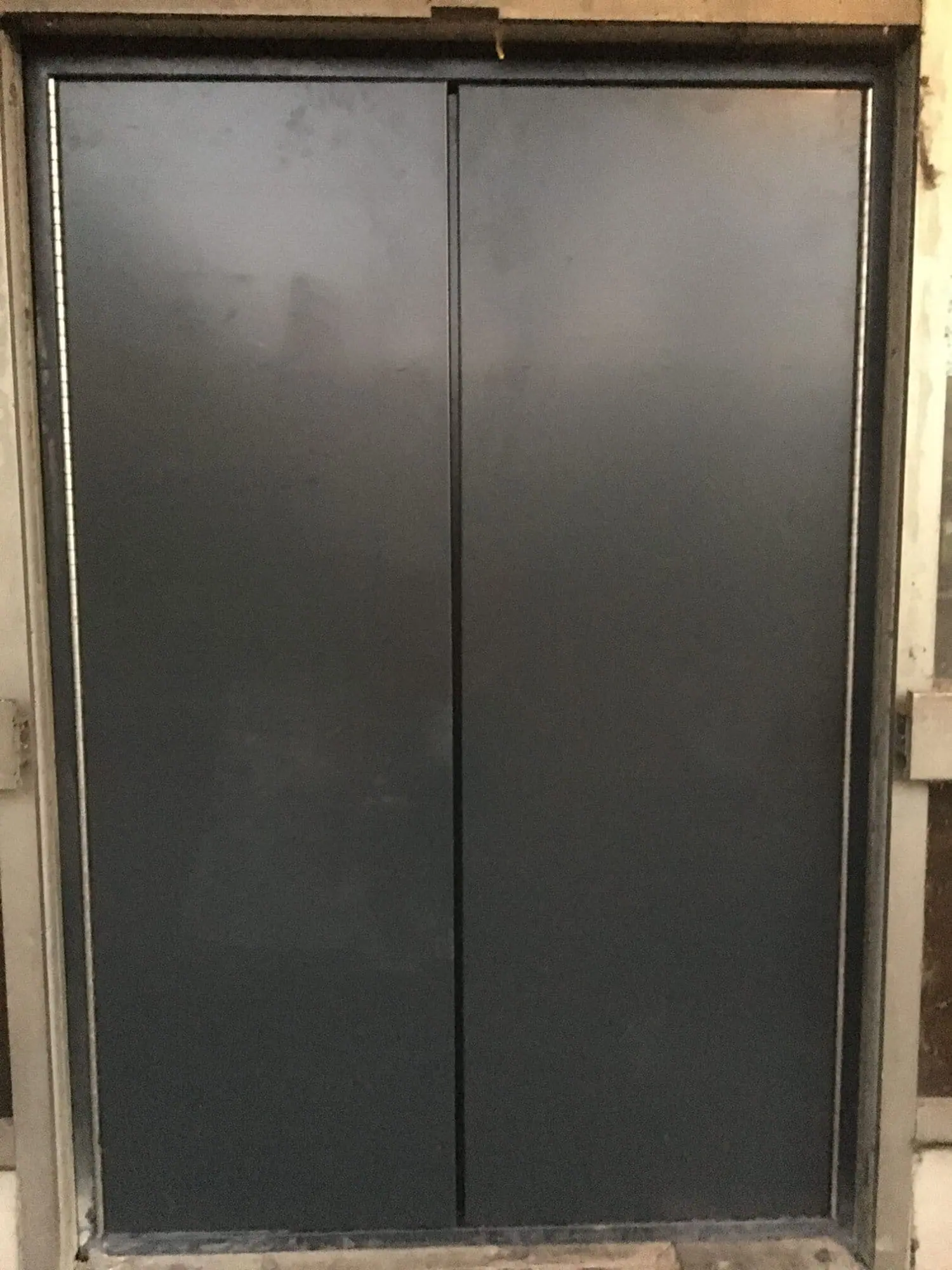 Pair of dark grey steel blast doors fitted flush in a frame