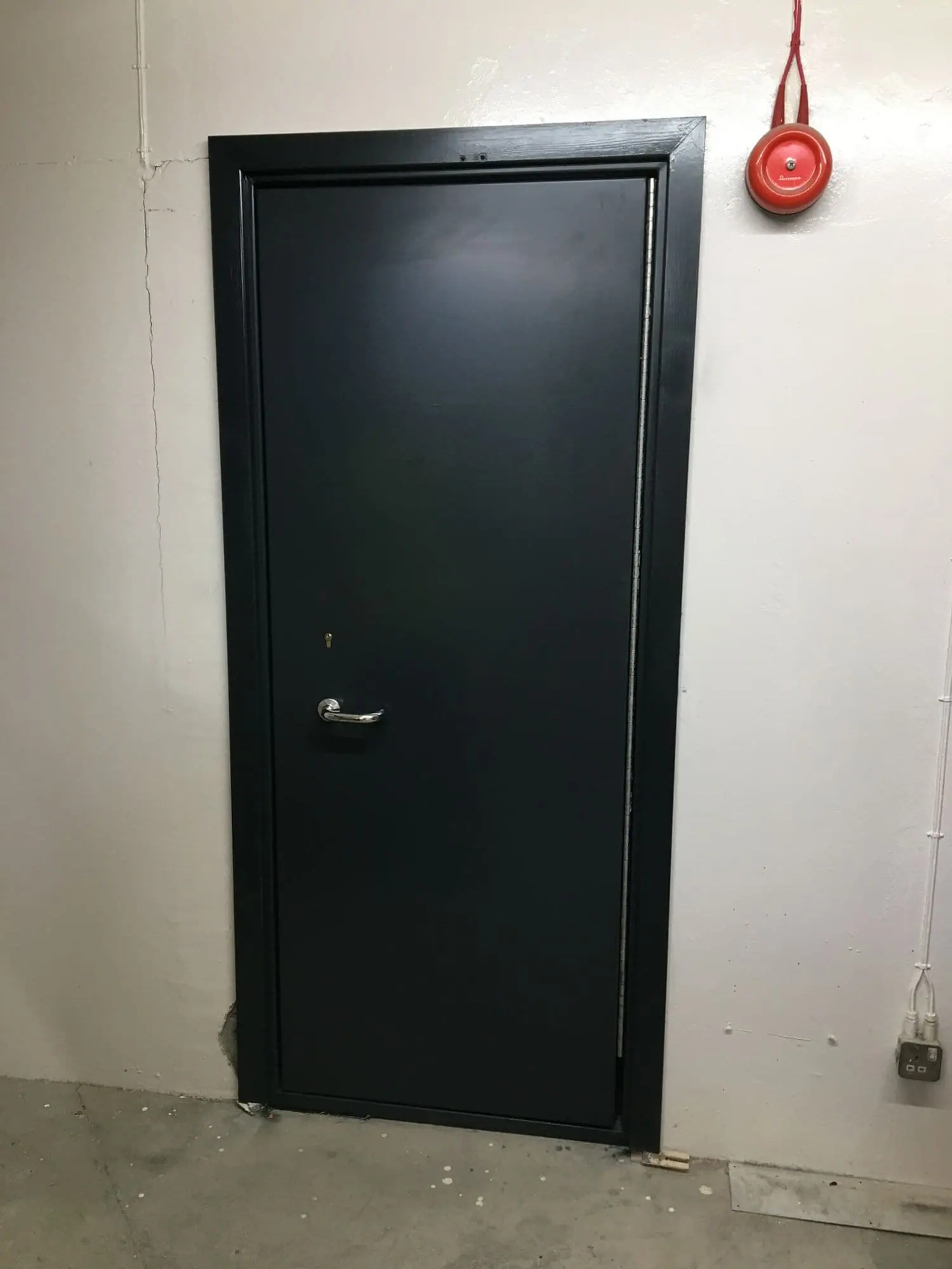 Single dark grey steel door with chrome lever handle and keyhole fitted in a plant room