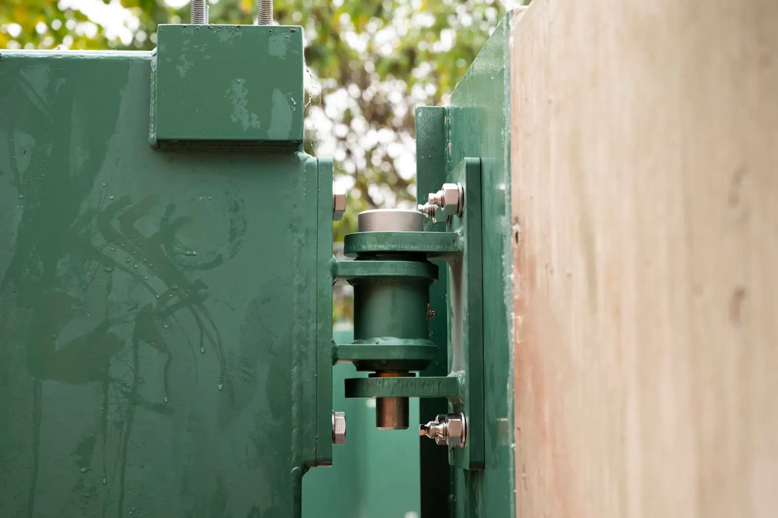 Close view of the hinge assembly and bolted brackets on a green flood gate